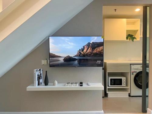 a living room with a flat screen tv on a wall at Metro sky prachachuen in Bang Su