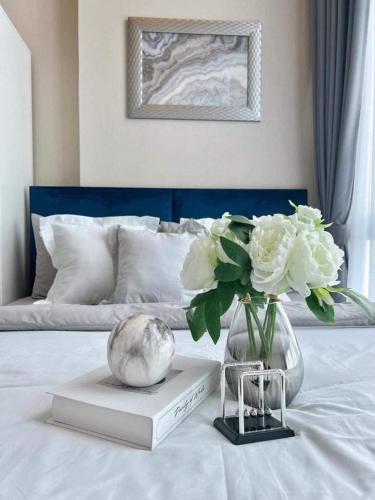 a vase of flowers on a book on a bed at Metro sky prachachuen in Bang Su