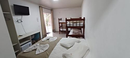 a bedroom with a bed and a desk and a television at Pousada Casa Amarela Brisa Parque in Penha