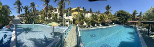a large swimming pool next to a building with palm trees at Coconut village in El Zapote