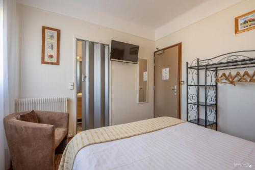 a bedroom with a bed and a chair and a television at Hotel La Roseraie in Fouras