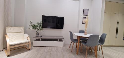Baku White City-Seaview Luxury Apartment في باكو: غرفة معيشة مع طاولة وكراسي وتلفزيون