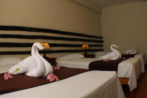 two swans sitting on beds in a hotel room at Chanchamayo Inn Hotel in La Merced