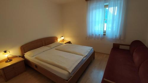 a bedroom with a bed and a window and a couch at Residence Ercabuan in Campitello di Fassa