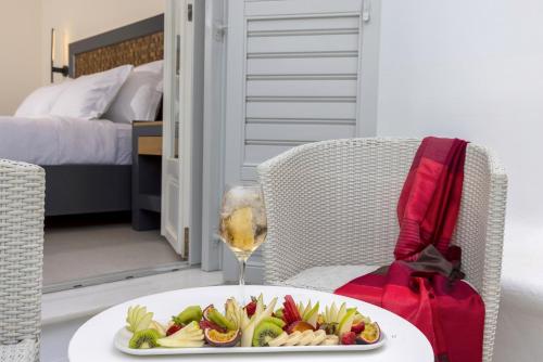 a plate of fruit on a table with a glass of wine at Petinos Hotel in Platis Yialos Mykonos