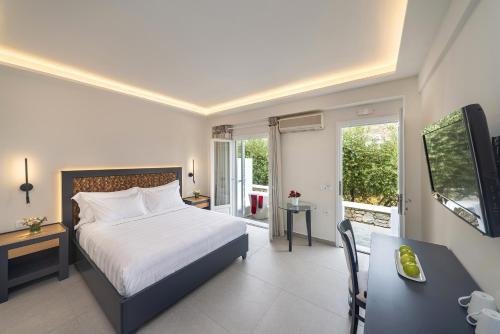 a bedroom with a bed and a desk and a television at Petinos Hotel in Platis Yialos Mykonos
