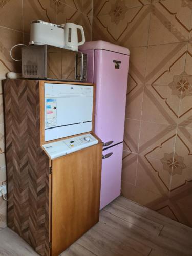 einen rosa Kühlschrank mit einer Mikrowelle darüber in der Unterkunft Elyam's Home 2 in Douala