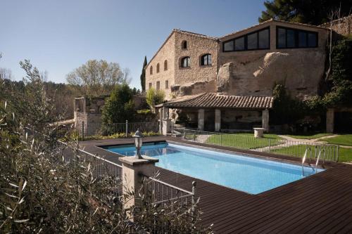 a house with a swimming pool in front of a building at Hotel Hort De Fortunyo in Arnés