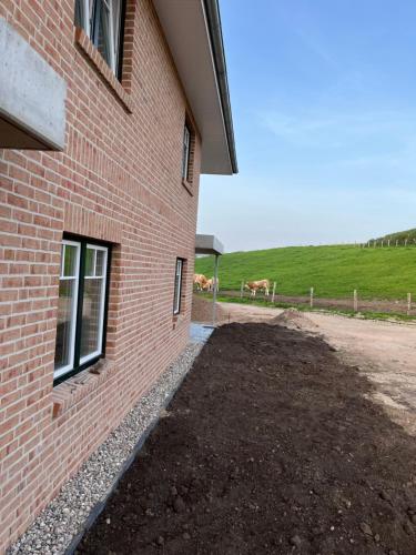 een kant van een bakstenen gebouw met twee paarden in een veld bij Ferienhof Theede in Neukirchen