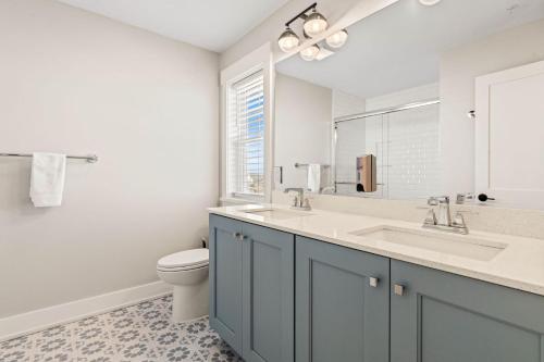 a bathroom with a sink and a toilet and a mirror at Island Enchantment by KEES Vacations in Kill Devil Hills