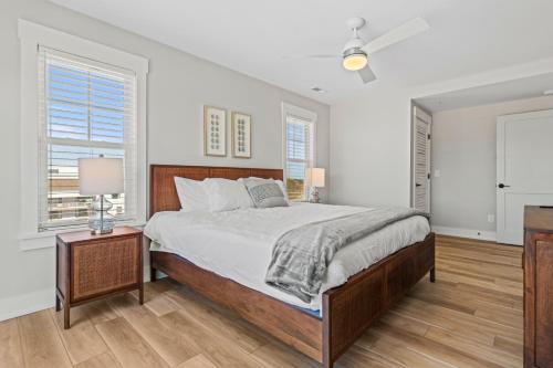 a bedroom with a large bed with white walls and wooden floors at Island Enchantment by KEES Vacations in Kill Devil Hills