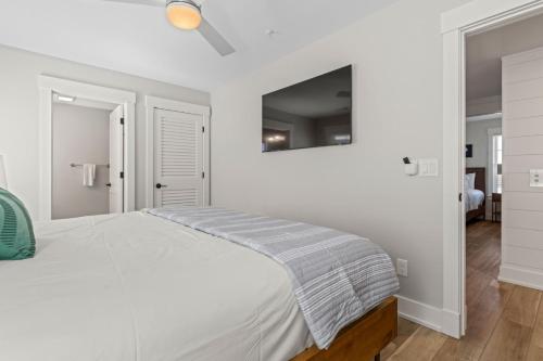 a white bedroom with a bed and a mirror at Island Enchantment by KEES Vacations in Kill Devil Hills