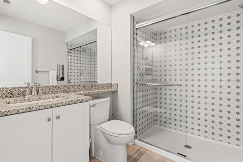 a white bathroom with a toilet and a shower at Island Enchantment by KEES Vacations in Kill Devil Hills