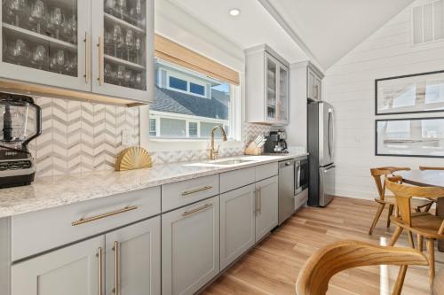 a kitchen with white cabinets and a table and chairs at Island Enchantment by KEES Vacations in Kill Devil Hills