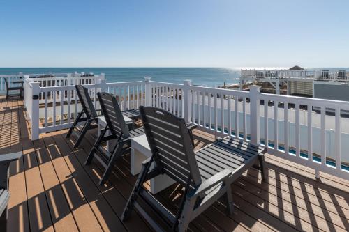 three chairs sitting on a deck overlooking the ocean at Island Enchantment by KEES Vacations in Kill Devil Hills
