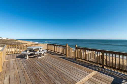 a wooden deck with a picnic table on the beach at Island Enchantment by KEES Vacations in Kill Devil Hills