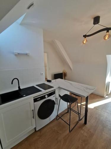 Il comprend une cuisine équipée d'une cuisinière, d'un évier et d'une table. dans l'établissement Le charmant de Lourmel appartement de 30m2 au calme, à Pontivy