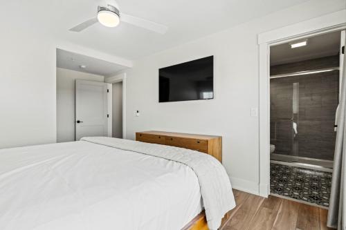 a white bedroom with a bed and a television at Island Enchantment by KEES Vacations in Kill Devil Hills