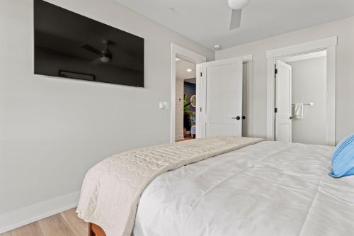 a white bedroom with a large bed and a flat screen tv at Island Enchantment by KEES Vacations in Kill Devil Hills