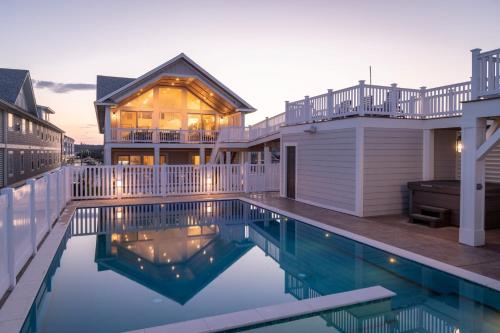 a house with a swimming pool in front of a house at Island Enchantment by KEES Vacations in Kill Devil Hills