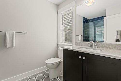 a white bathroom with a toilet and a sink at Island Enchantment by KEES Vacations in Kill Devil Hills