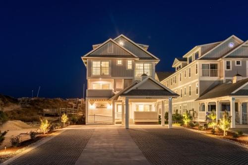 a large white house with a driveway at night at Island Enchantment by KEES Vacations in Kill Devil Hills