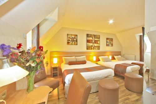 um quarto de hotel com duas camas e um sofá em Hostellerie du Causse em Gramat