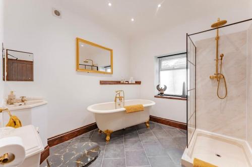 a bathroom with a tub and a shower and a sink at Logan Lodge, Great Yarmouth - for your large group! in Great Yarmouth