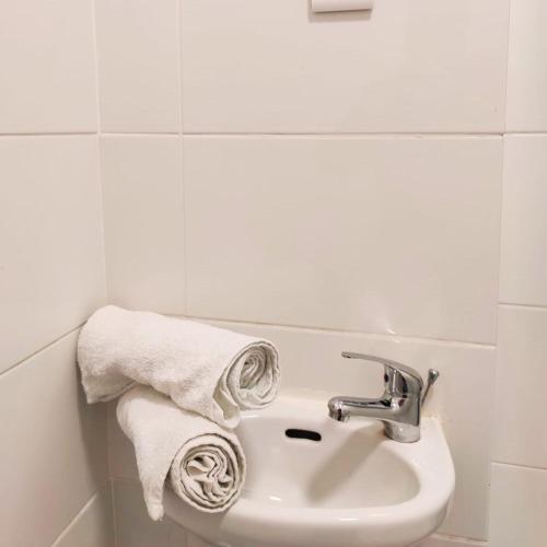 a bathroom with a sink and towels on a wall at Liberdade Home Royal direito in Braga
