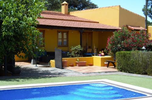 a house with a swimming pool in front of a house at Gemütliches Ferienhaus in El Rosario mit Privatem Pool und Panoramablick in El Rosario