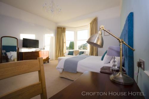 um quarto de hotel com uma cama e uma secretária com um candeeiro em Crofton House Hotel em Torquay