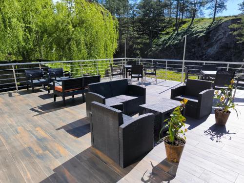 eine Terrasse mit schwarzen Stühlen, Tischen und Bäumen in der Unterkunft Vila POGLED Wellness i spa in Divčibare