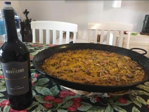 una pizza en una sartén sobre una mesa con una botella de vino en Habitación en chalet cerca de la playa en Benicasim, en Benicàssim