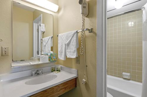 La salle de bains est pourvue d'un lavabo, d'un miroir et d'une baignoire. dans l'établissement Relax Inn, à Alexandria