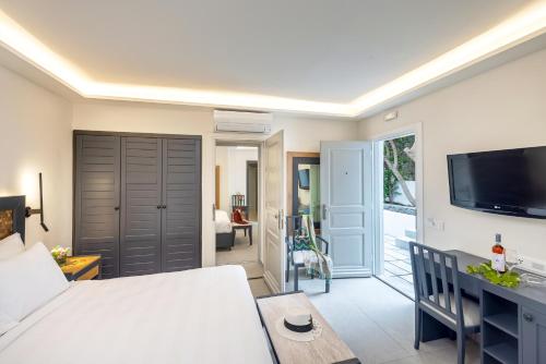 a bedroom with a bed and a desk and a tv at Petinos Hotel in Platis Yialos Mykonos