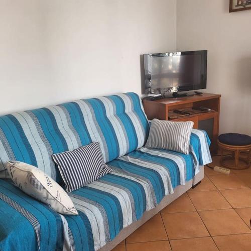 a blue couch in a living room with a tv at Tavira Garden Pool Apartment Algarve in Tavira