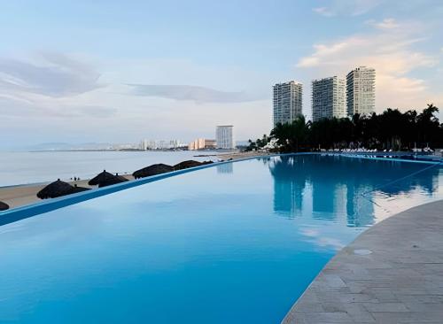 une grande piscine au bord de l'eau avec des bâtiments dans l'établissement Condominio con las mejores vistas de la bahía, à Bucerías