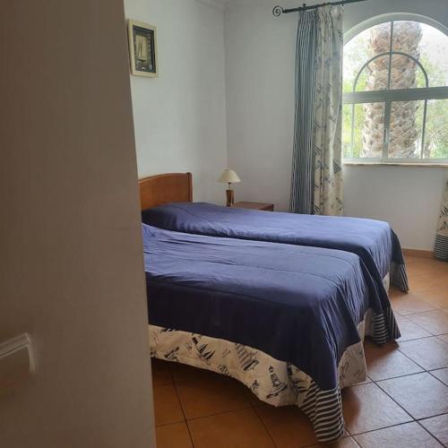 a bedroom with a blue bed with a window at Tavira Garden Pool Apartment Algarve in Tavira