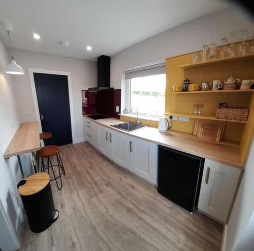 a kitchen with white cabinets and a sink and a window at PatsView Lodge in Donegal