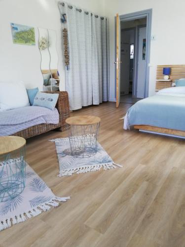 a bedroom with a bed and a couch and wooden floors at L'HORIZON Vue mer et falaises in Fécamp