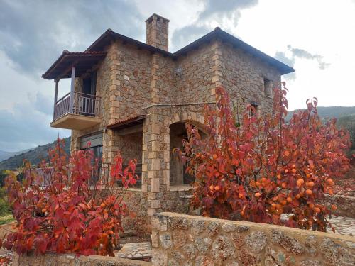 a stone house with a balcony and red plants at Konstantina 4 in Ambelókipoi