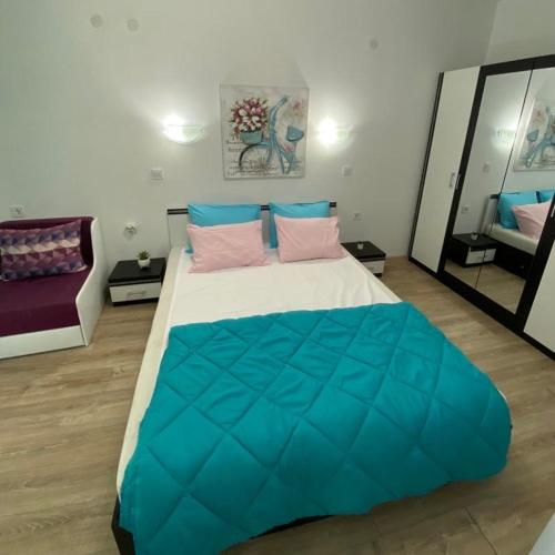 a bedroom with a large bed with blue and pink pillows at Апартамент за гости ДЕНИЦА in Obzor