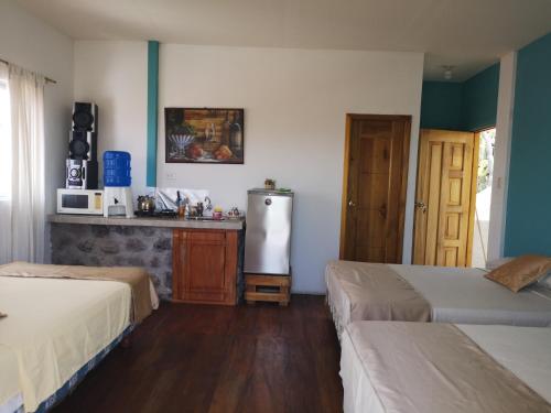 a room with two beds and a refrigerator at Hostal Cabañas Don Jorge in Puerto Baquerizo Moreno