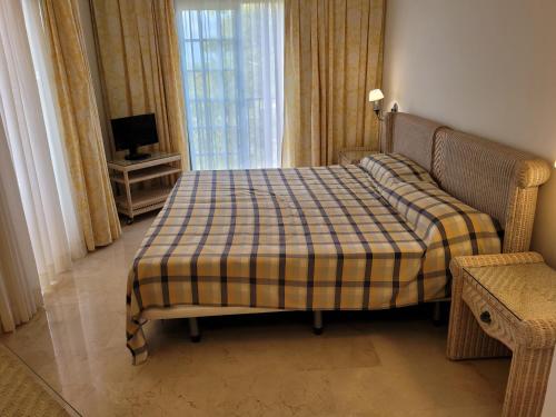 a bedroom with a bed with a plaid blanket on it at Palm Oasis - Time Sharing in Las Palmas de Gran Canaria