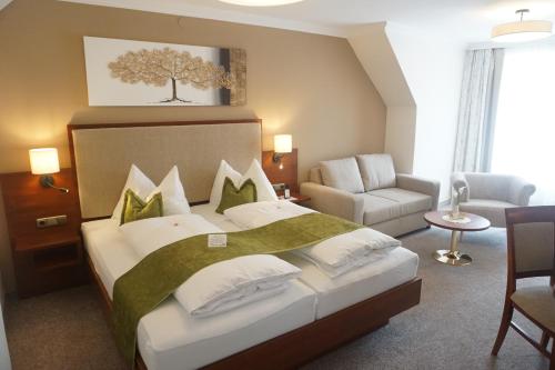 um quarto com uma cama, um sofá e uma cadeira em Gartenhotel Kloepferkeller em Eibiswald