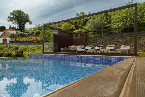 a swimming pool with chairs and a fire place next to a building at Casa da Quebrada, Douro in Lamego