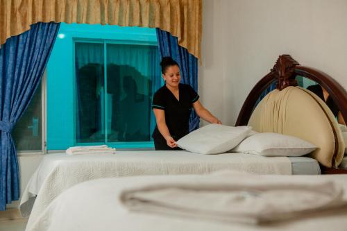 a woman standing next to a bed in a room at Hotel La Cascada - Lago Agrio in Nueva Loja