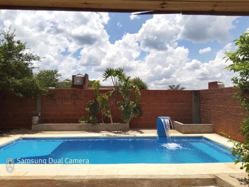 Una piscina en un patio trasero con una pared de ladrillos. en Cunumí, en Puerto Iguazú