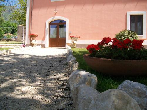a house with red flowers in front of a building at Agriturismo La Palazza in Sala Consilina