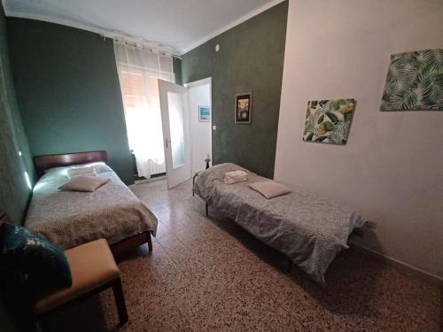 two beds in a room with green walls at La Casa Rossa -Dimora di campagna in Montechiaro D'acqui